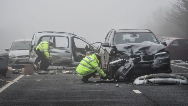A Thames Valley Police collision investigator takes notes by damaged vehicles on the A40 near Witney, Oxfordshire, after a woman died following a pile-up which involved around 20 vehicles.